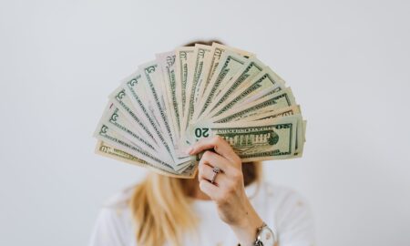 woman holding fan of us dollar bills