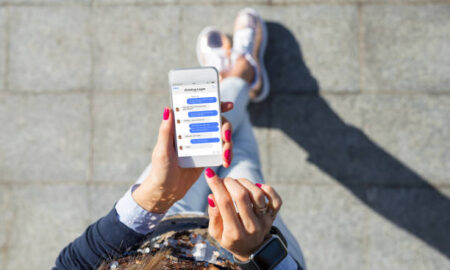 Woman using instant messaging app on mobile phone, view from above